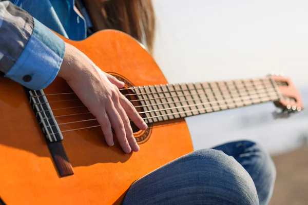 Close up shot without face. Woman playng guitar an the coast — Stock Photo, Image