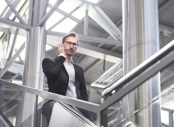 Man on smart phone - young businessman in airport. Handsome serious men in eyeglasses wearing suit jacket indoors — Stock Photo, Image