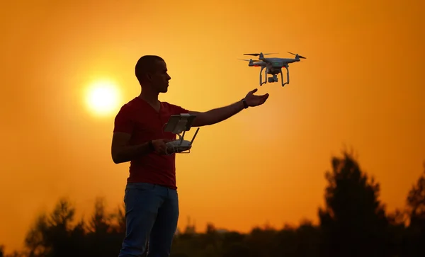 El hombre controla un cuadrohelicóptero. Foto cálida puesta de sol — Foto de Stock