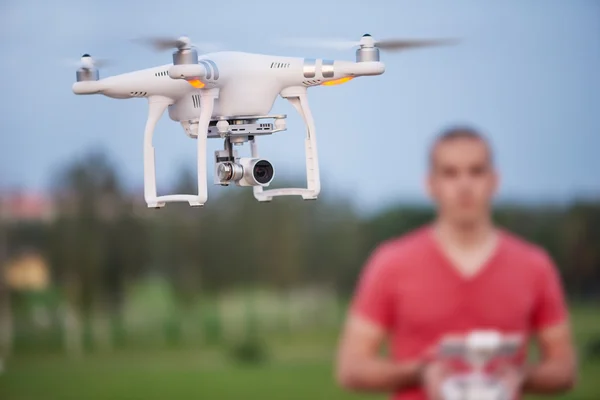 El hombre controla un cuadrohelicóptero. Enfoque selectivo en el dron, los hombres está borrosa — Foto de Stock