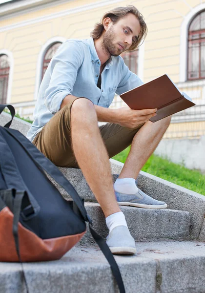 Stoppelstudent liest auf der Treppe der Universität ein Buch — Stockfoto