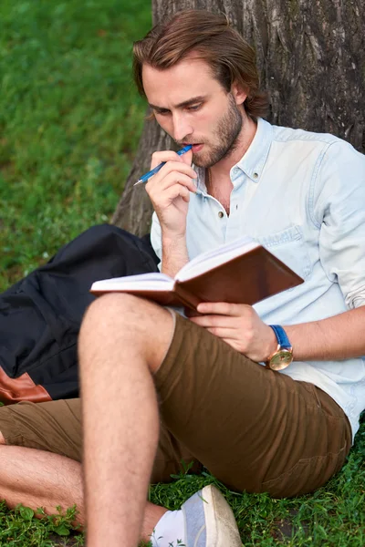 Seriöser Student liest im Park des Campus ein Buch — Stockfoto