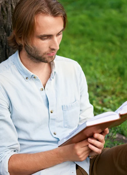 Seriöser Student liest im Park des Campus ein Buch — Stockfoto