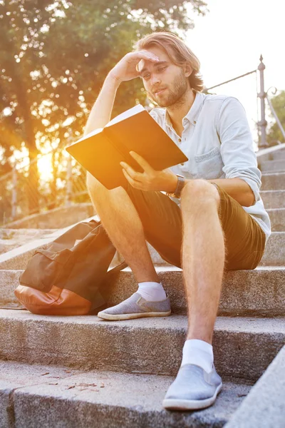 Student liest auf der Treppe im Campus ein Buch — Stockfoto