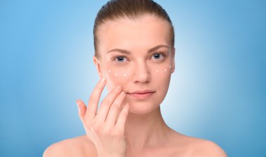 Kadın kaldırma krem yüz, üzerinde mavi arka plan uygulanıyor..