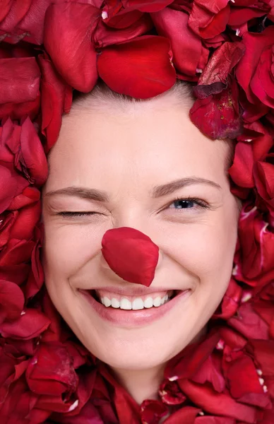 Hermosa mujer feliz acostada en rosas pétalos — Foto de Stock