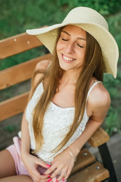 Весела молода жінка з закритими очима на лавці в парку — стокове фото