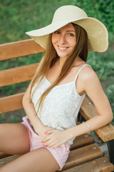 Uśmiechnięta młoda kobieta na ławce w parku — Zdjęcie stockowe