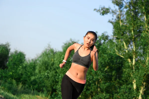 Fitte junge asiatische Frau joggt im Park — Stockfoto