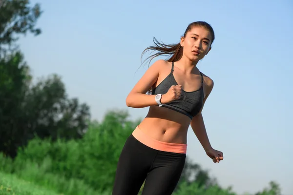 Sportliche junge asiatische Frau joggt im Park — Stockfoto