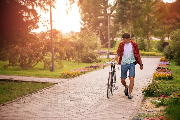 Hipster man med cykel promenader i parken — Stockfoto