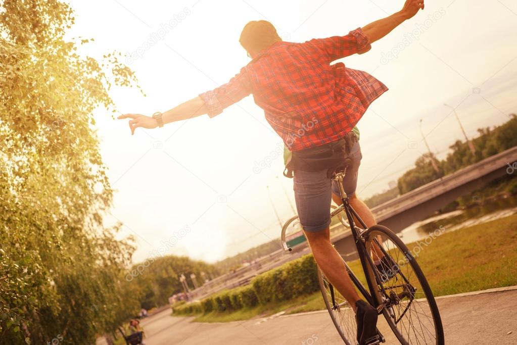 Hipster on bike at the city in sunset