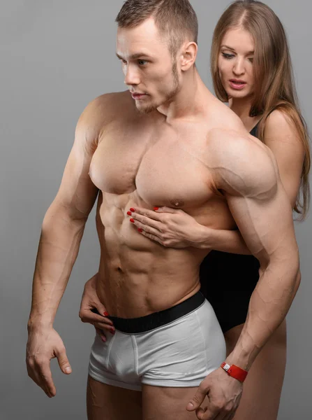 Casal sensual de fisiculturista e mulheres fitness em fundo cinza — Fotografia de Stock