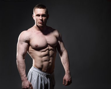 Onun kas kas gömleksiz adam koyu arka plan üzerinde Studio gösterir.