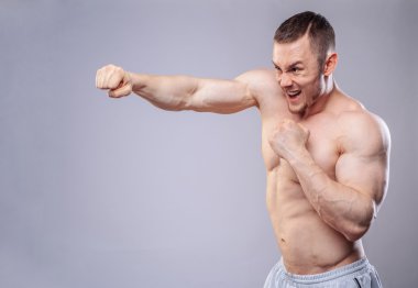 Erkek boxer eğitim yumruklar gri arka plan üzerinde yapma