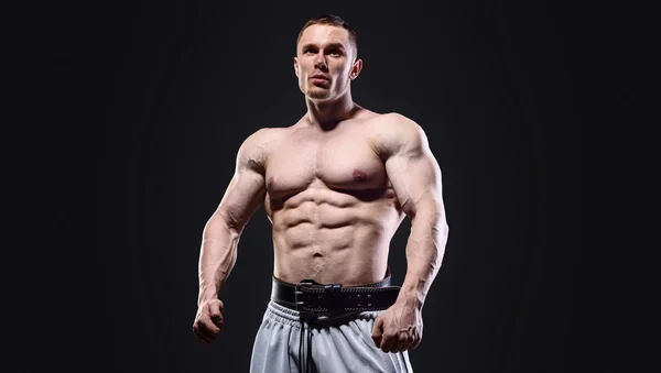Homem muscular com cinto de elevação posando sobre fundo escuro — Fotografia de Stock