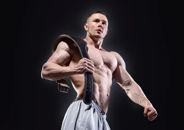 Starker muskulöser Mann mit Hebegürtel, der vor dunklem Hintergrund posiert — Stockfoto