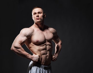 Strong muscular man posing in studio over dark background 