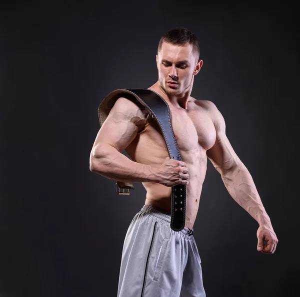 Strong muscular man with lifting belt posing over dark backgroun — Stock fotografie
