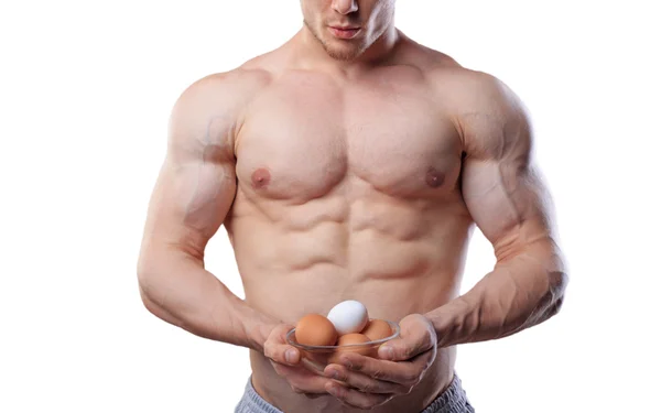 Homem atleta sem camisa mostrando copo com ovos em fundo branco isolado — Fotografia de Stock