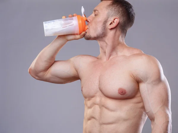 Athlete man drinking protein over grey background — ストック写真