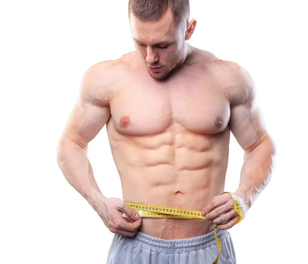 Image of muscular man measure his waist with measuring tape in centimeters. Shot isolated on white background — Stock Photo, Image