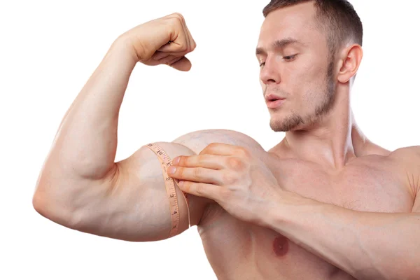 Image of muscular man measure his biceps with measuring tape in centimeters. Isolated on white backgound — ストック写真