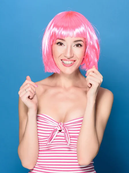 Retrato de bela jovem sorridente com cabelo rosa em um fundo azul — Fotografia de Stock