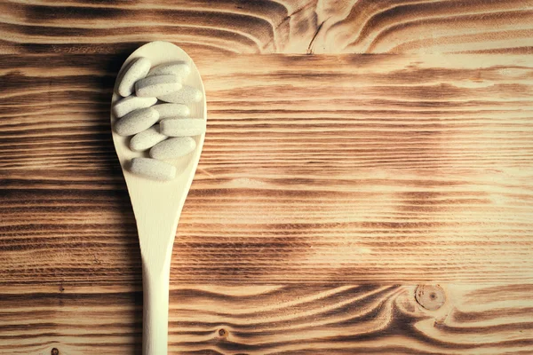 Witaminy i suplementy w drewnianą łyżką na zachwycający łakocie — Zdjęcie stockowe