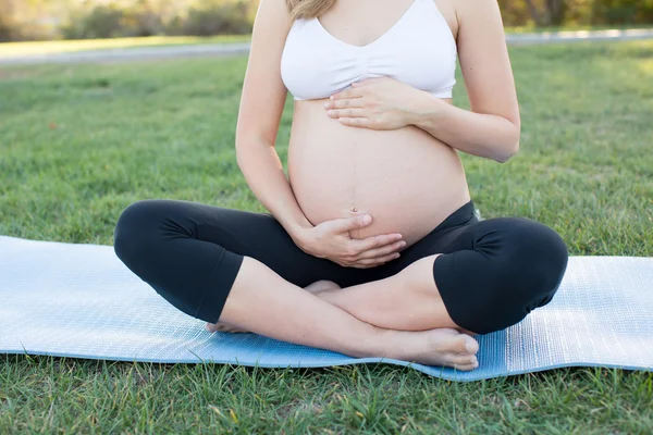 Mujer embarazada haciendo yoga afuera — Foto de Stock
