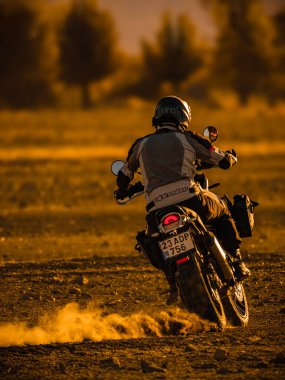 Yolda siyah sırt çantalı motosikletli bir adam var.