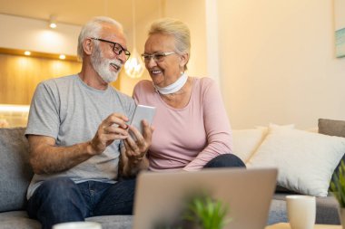 Üst düzey çift evde dizüstü bilgisayar kullanıyor. İnternetten alışveriş. İnsanlar ve teknoloji konsepti..