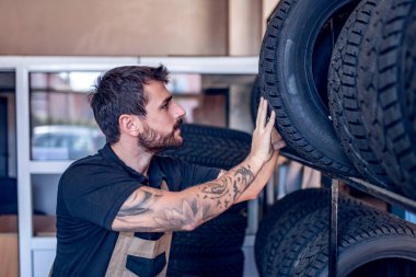 Tamirhanede lastik tutan bir tamirci. Kış ve yaz lastiklerinin değiştirilmesi.