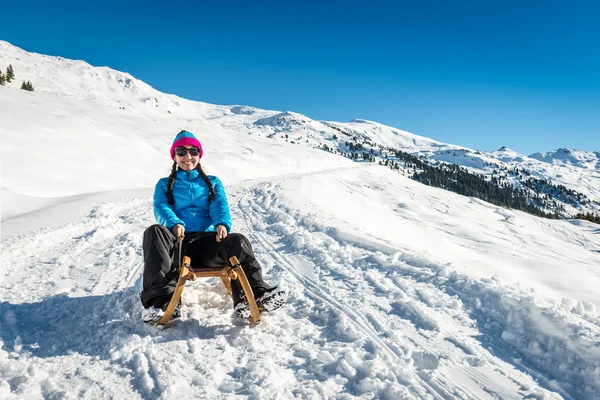 Lächelndes Mädchen auf einem Schlitten im Schnee — Stockfoto