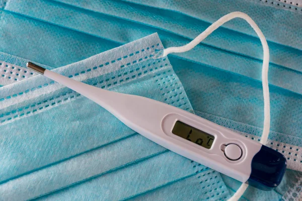 White thermometer on disposable surgical masks.