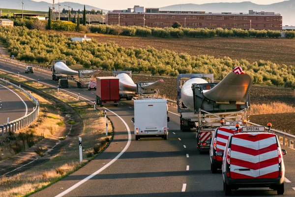 Special transport of wind turbine blades. Several trucks with wind turbine blades circulating on the highway with beacon vehicles behind to warn other road users of the danger.