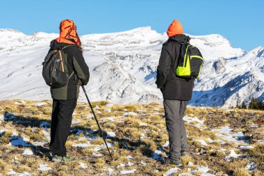 İki yürüyüşçü, Sierra Nevada dağlarının karlı manzarasını inceliyor..