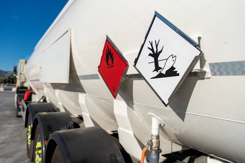 Flammable and environmental contaminant hazard labels on a tank truck with dangerous goods.