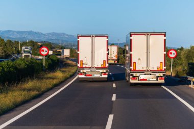 Otobanda birden fazla kamyon var. Bunlardan biri de geçilmesi yasak bir bölgede yasadışı sollama yapmak.