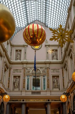 Brüksel, Belçika - 30 Kasım 2025: Şenlikli Noel süsleri ve simgesel cam çatısı altında Galerie de la Reine 'i süsleyen altın ışıklar.