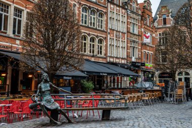 Leuven, Belçika - 14 Aralık 2025: De Kotmadam bronz heykeli Fred Bellefroid tarafından Oude Markt meydanında, tarihi Flaman binaları ve boş kafe teraslarıyla çevrili.