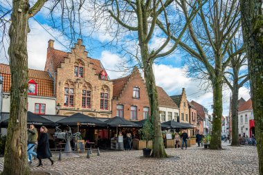 Bruges, Belçika - 14 Şubat 2026: İnsanlar tarihi evlerin önünden geçiyor ve Zeus, Leda, Prometheus ve Pegasus heykeli Brüksel 'deki Walplein' de.