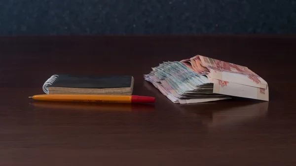 Um pacote de dinheiro e Bloco de notas com caneta — Fotografia de Stock