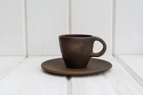 Clay cup and saucer  on a white wooden background — Stock Photo, Image
