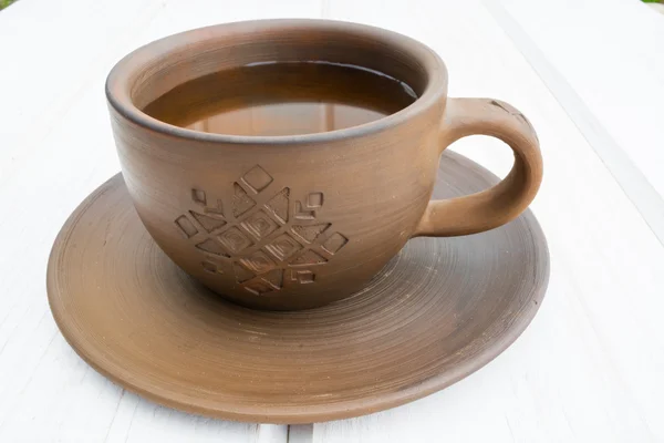 Clay cup and saucer  on a white wooden background — Stock Photo, Image