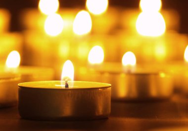 Arka planı bulanık, siyah bir masada sarı alevli mumlar yakmak. Noel mumları. Geceleri kilisede mum yakardı.