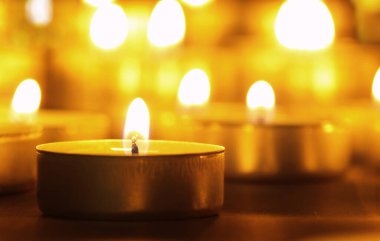 Arka planı bulanık, siyah bir masada sarı alevli mumlar yakmak. Noel mumları. Geceleri kilisede mum yakardı.