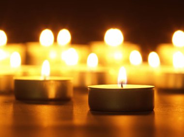 Arka planı bulanık, siyah bir masada sarı alevli mumlar yakmak. Noel mumları. Geceleri kilisede mum yakardı.