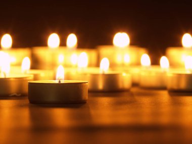 Arka planı bulanık, siyah bir masada sarı alevli mumlar yakmak. Noel mumları. Geceleri kilisede mum yakardı.