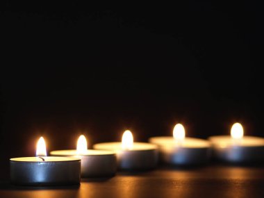 Arka planı bulanık, siyah bir masada sarı alevli mumlar yakmak. Noel mumları. Geceleri kilisede mum yakardı.